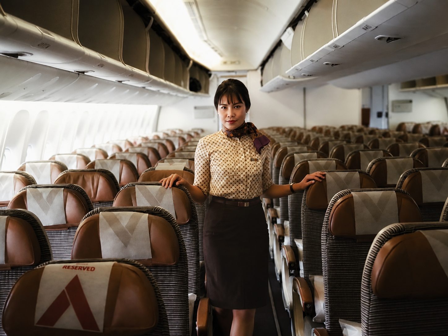 A flight attendant standing quietly in an aircraft cabin